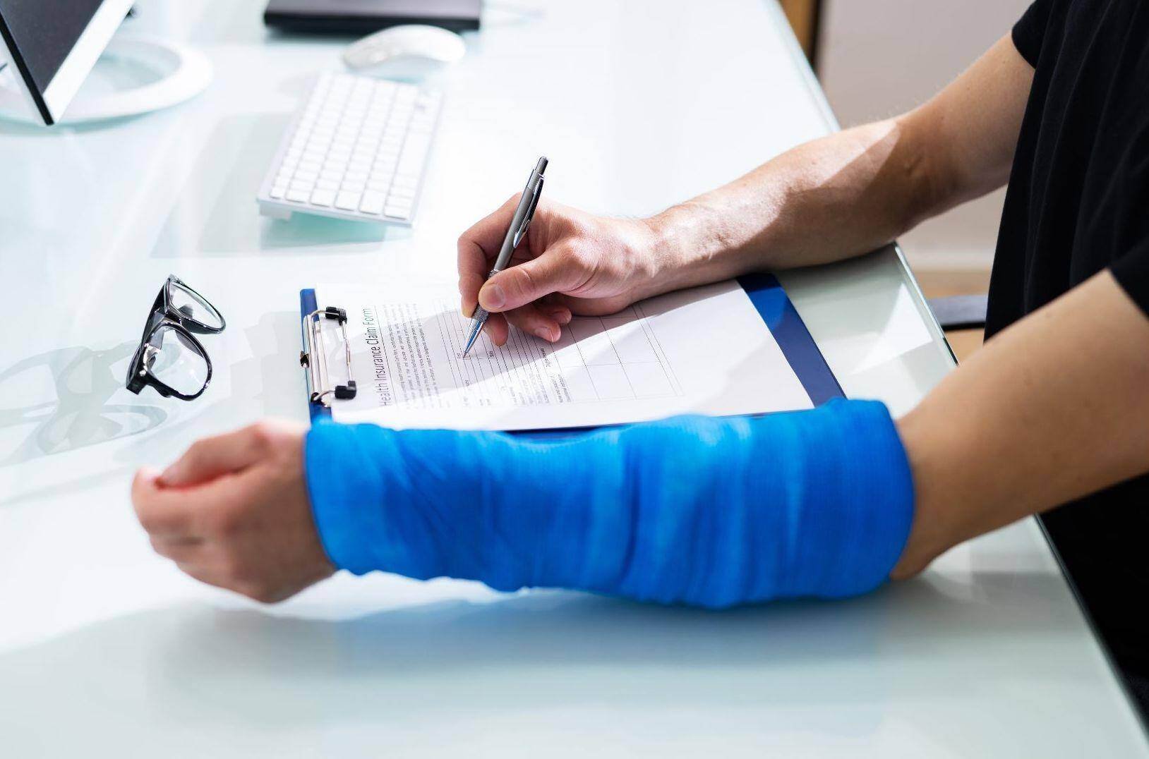 A car accident victim filling out an insurance claim with a broken arm in Jersey City, New Jersey